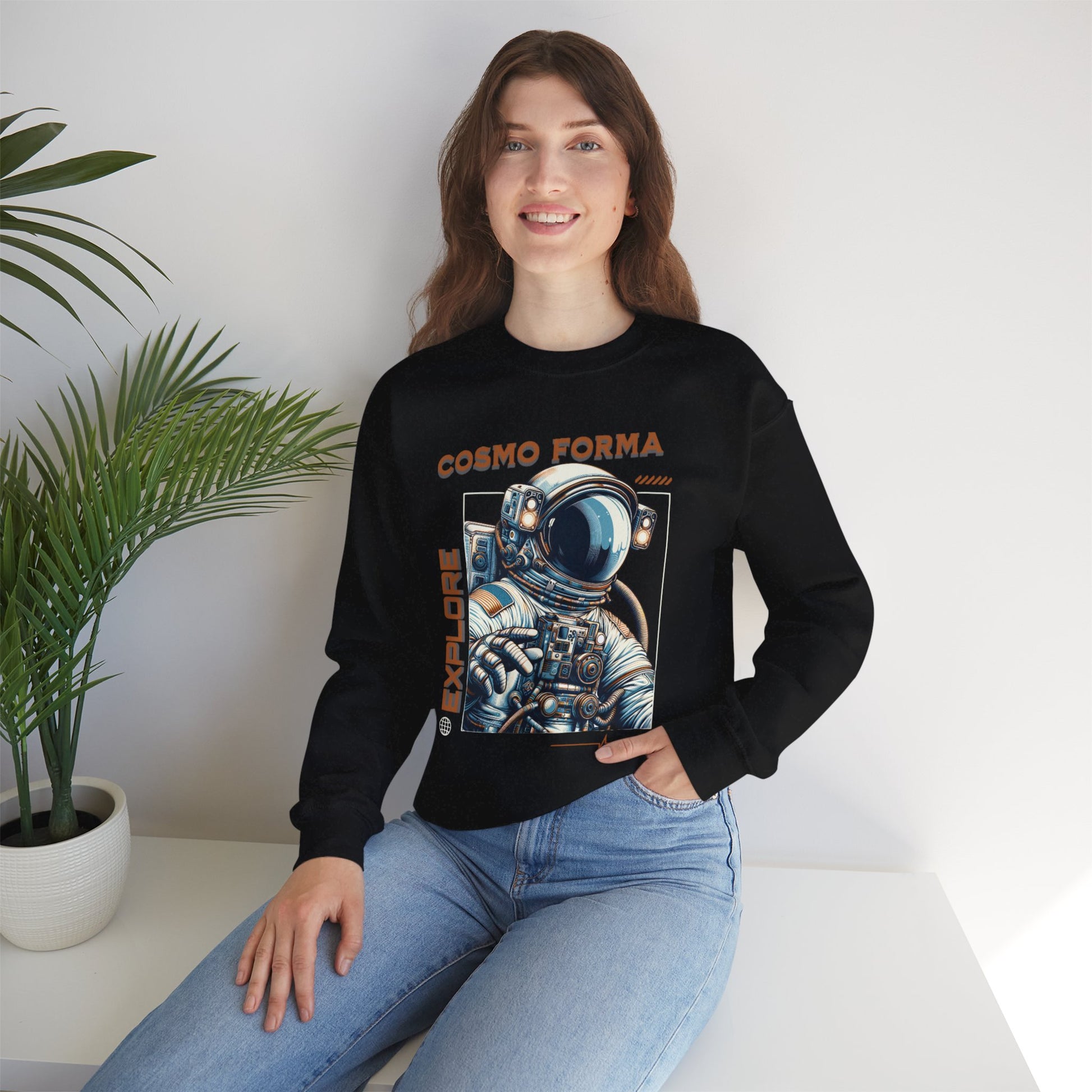 Person wearing a black sweatshirt with an astronaut graphic and 'Cosmo Forma' text, sitting on a white surface with a plant in the background.
