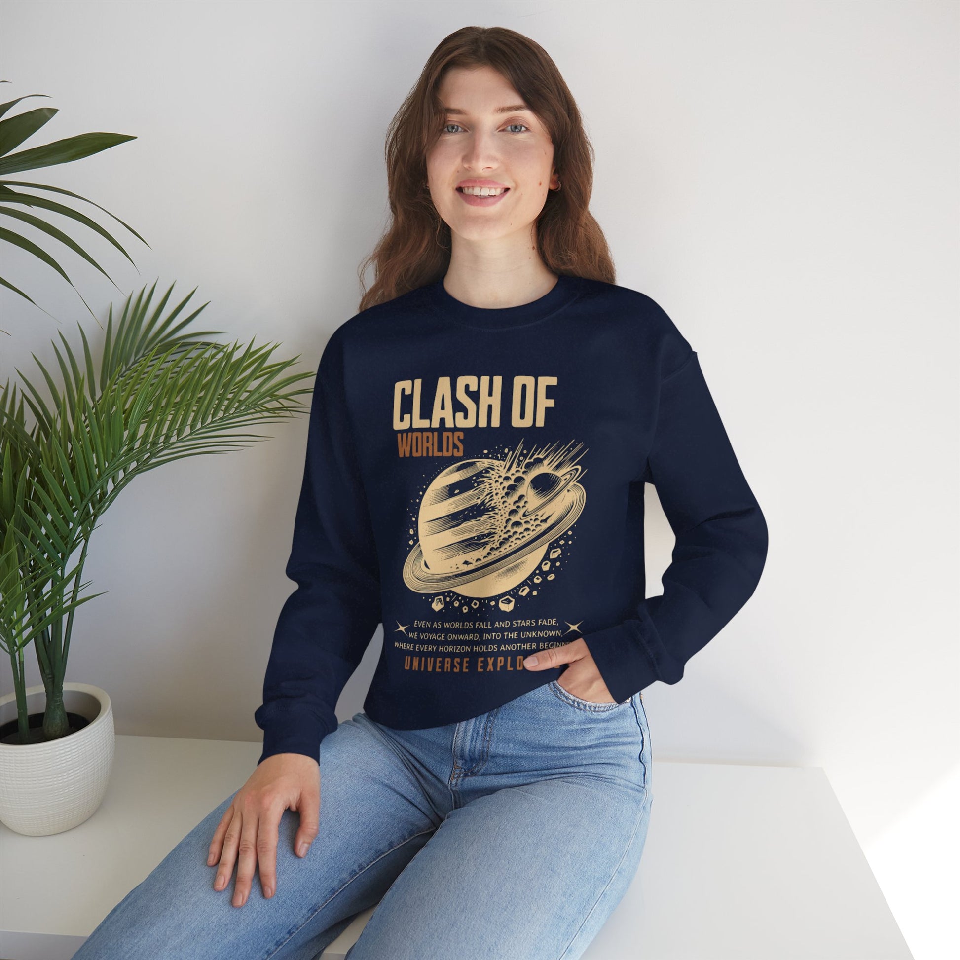 Person wearing a navy blue sweatshirt with 'Clash of Worlds' design, sitting on a white surface with a plant in the background.