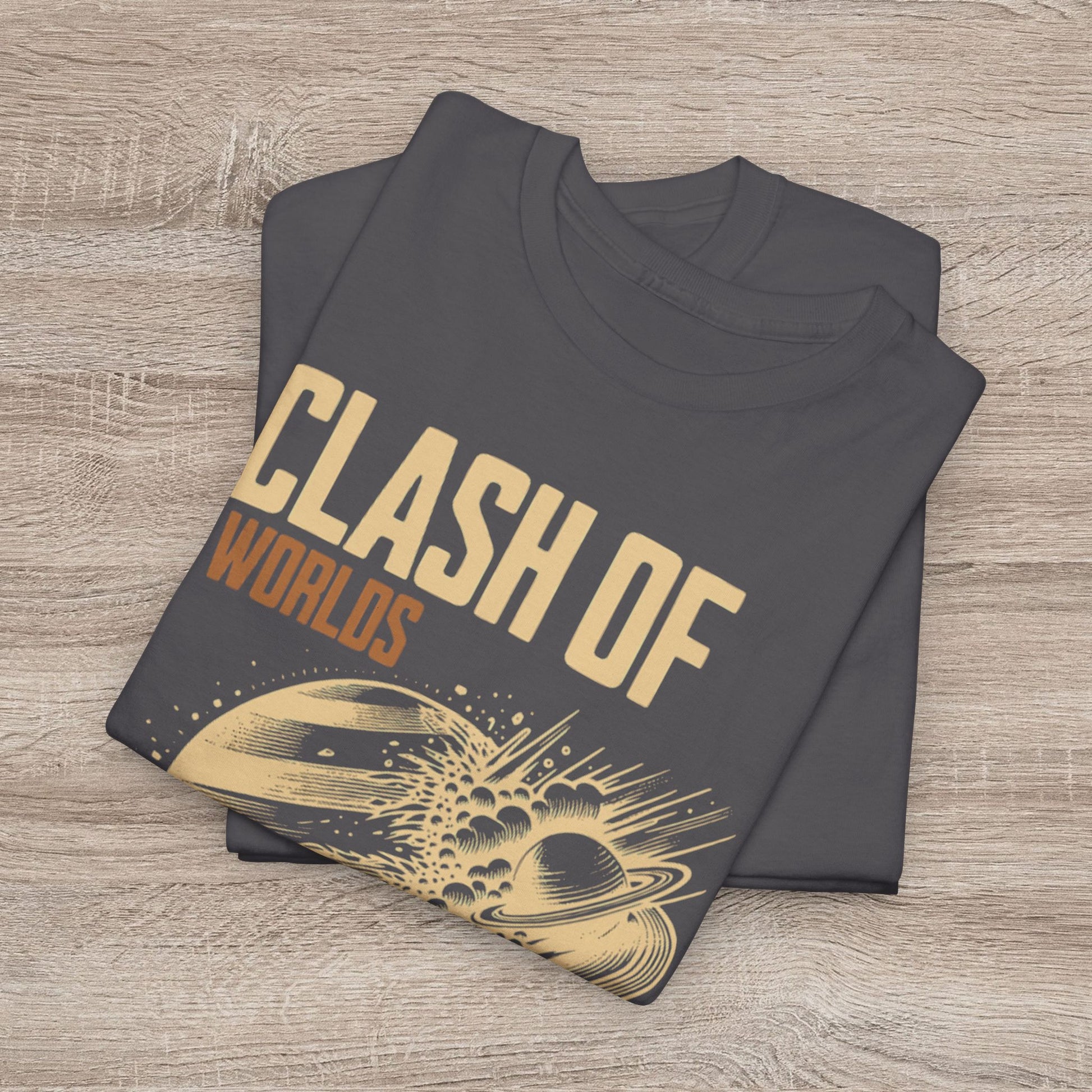 Folded dark gray t-shirt with 'Clash of Worlds' text and space-themed design on a wooden surface