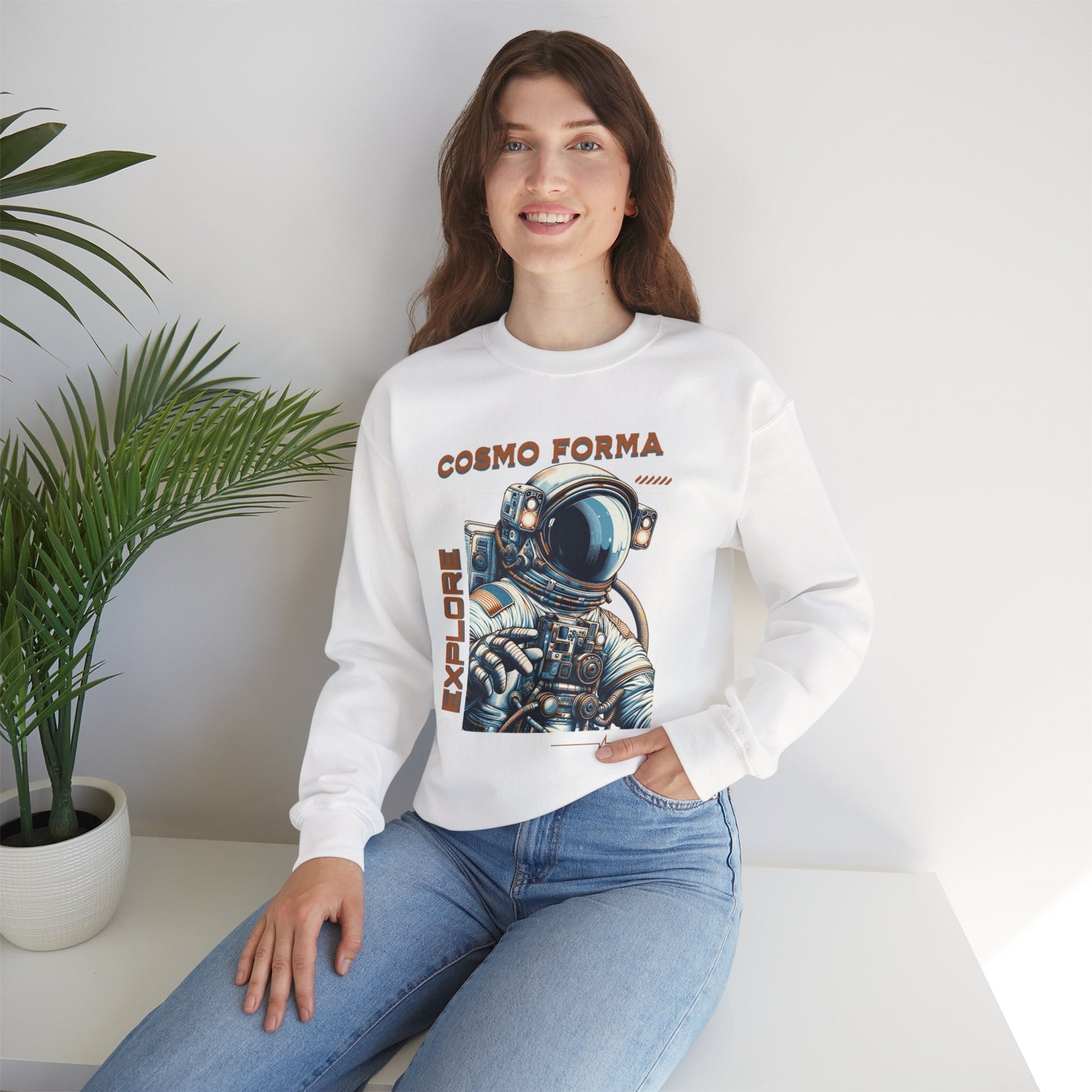 Woman wearing a white sweatshirt with an astronaut graphic and 'Cosmo Forma' text, sitting in a room with a plant.